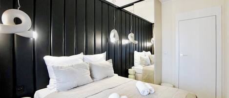 A modern hotel room with a large bed, white bedding, and a black accent wall.