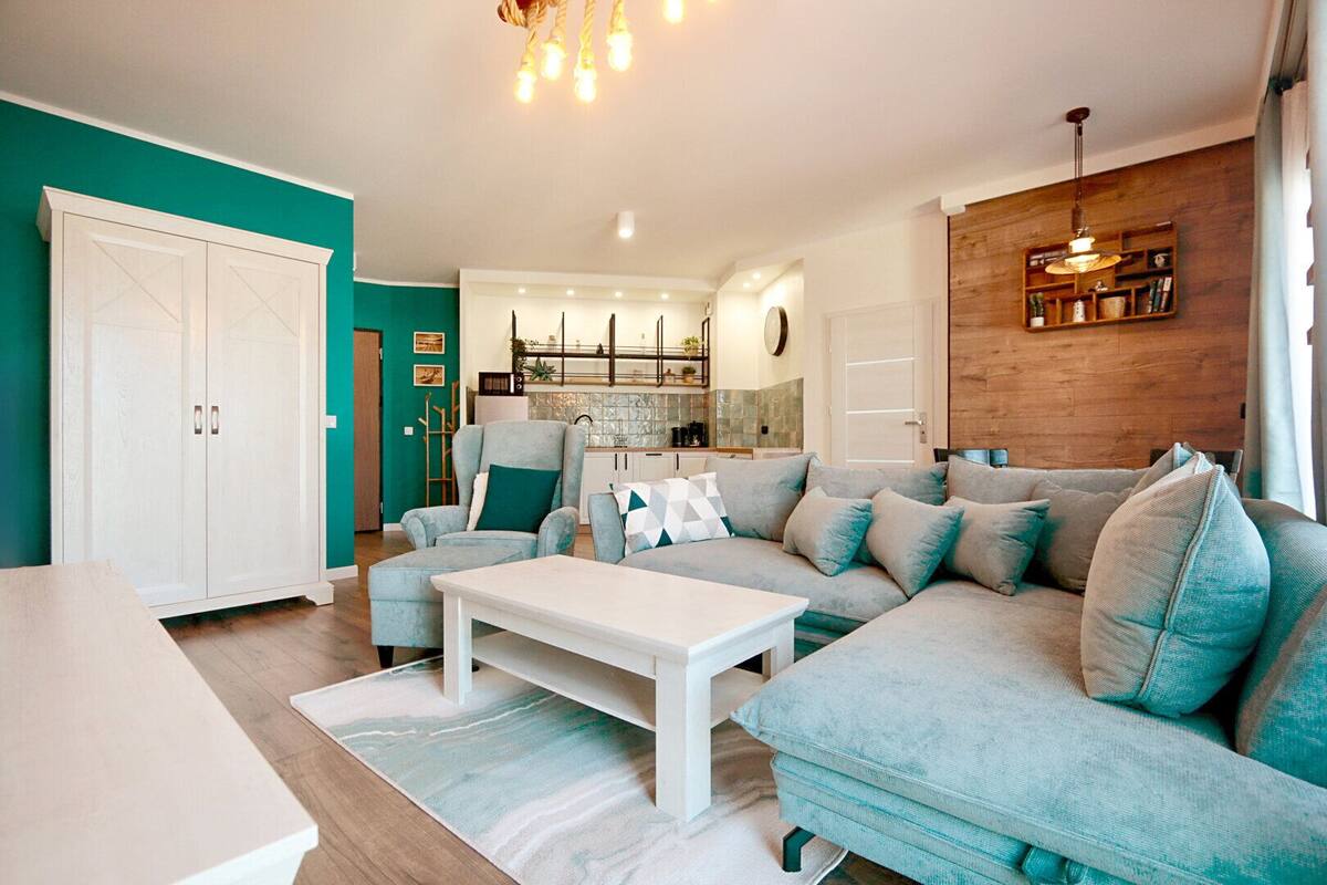 A modern living room with a sofa set, a dining table, and a kitchen in the background.