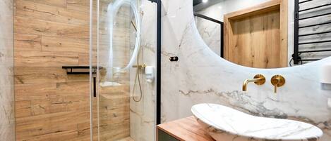 A modern bathroom with a glass-enclosed shower, a marble sink, and a wooden vanity.