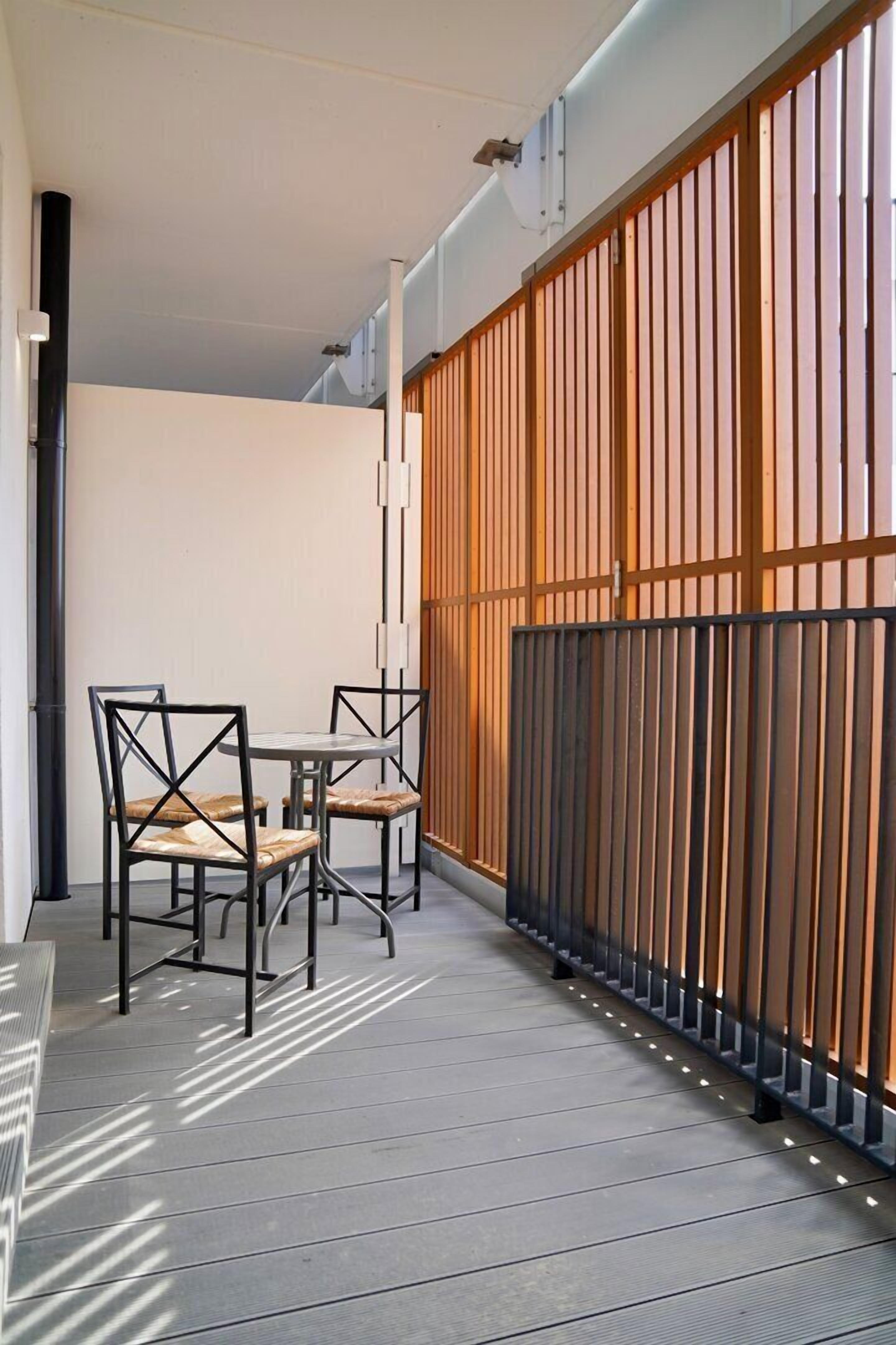 A balcony with a wooden fence, a table, and chairs.