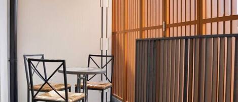 A balcony with a wooden fence, a table, and chairs.