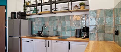 Een moderne keuken met witte kasten, een roestvrijstalen koelkast, een zwarte koffiezetapparaat en een houten aanrecht.