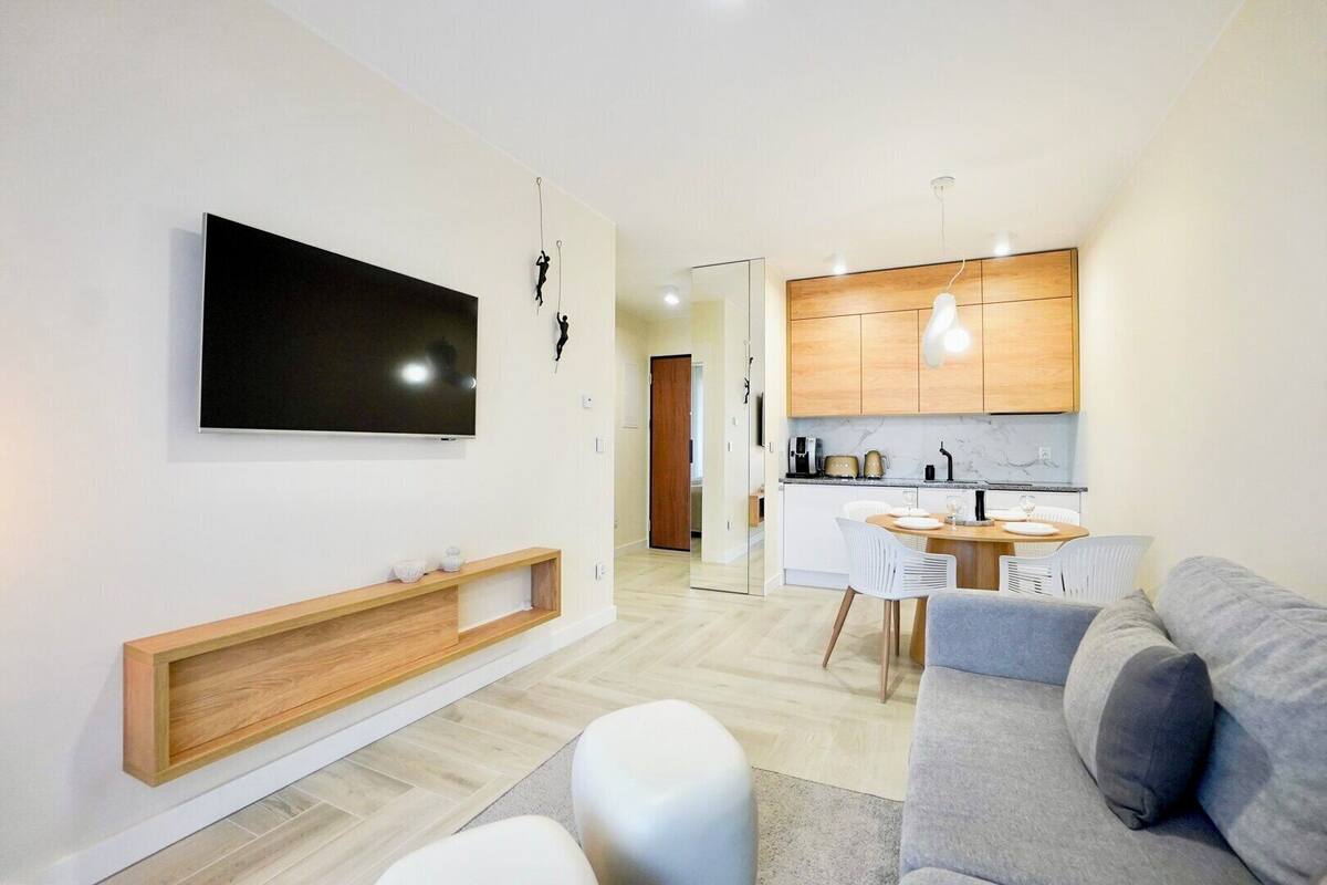 A modern living room with a flat-screen TV, a grey sofa, and a wooden entertainment unit.