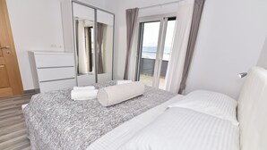 A hotel room with a bed, a dresser, a mirror, and a balcony with curtains. - Villa Sana, on the beach with swimming pool (Vir)