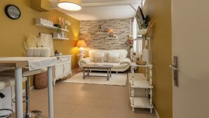 Ein modernes Wohnzimmer mit einer Couch, einem Couchtisch und Dekoration. Es gibt einen Essbereich mit Tisch und Stühlen. Der Raum verfügt über eine Steinwand und eine gelbe Akzentwand.