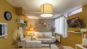 Ein modernes Wohnzimmer mit Steinwand, einer Couch, einem Couchtisch und einem an der Wand befestigten Fernseher.