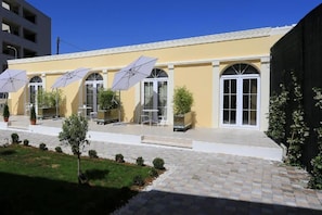 A building with a yellow facade, large arched windows, and outdoor seating with umbrellas. - Guesthouse Villa Maggie (Zadar)
