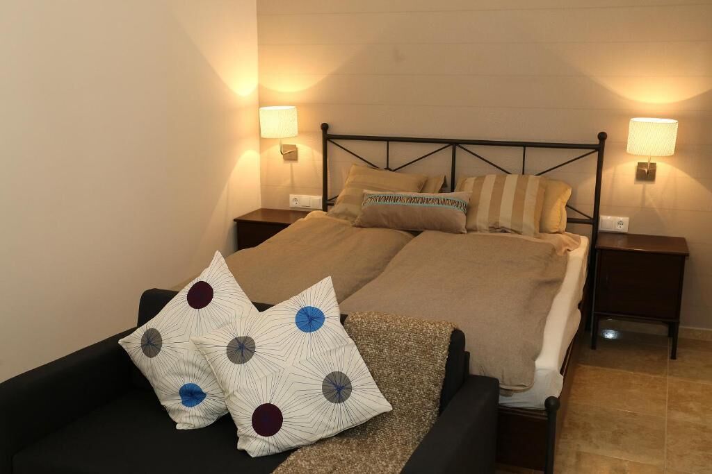 A double bed with a headboard, two bedside tables, and two wall-mounted lamps.