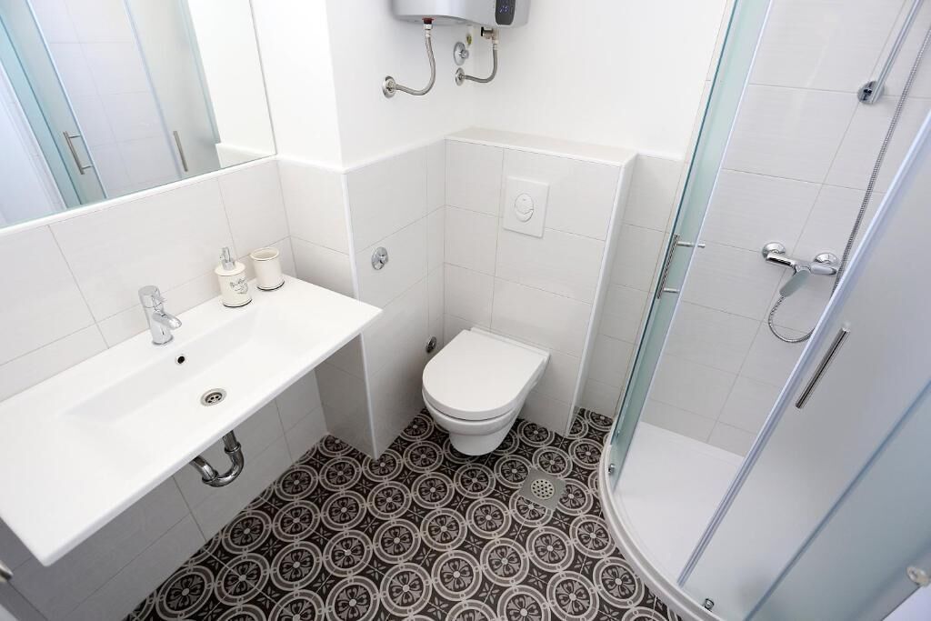 A bathroom with a white sink, toilet, and shower.