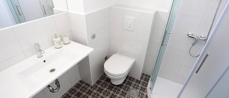A bathroom with a white sink, toilet, and shower.