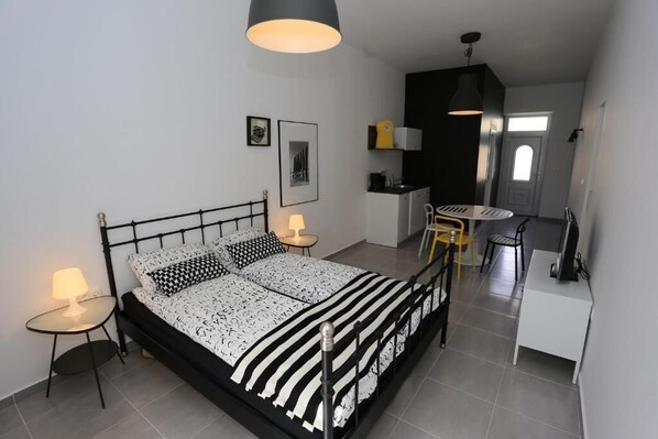 Una habitación pequeña con cama, mesitas de noche, escritorio y una silla.
