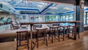 A modern bar area with high ceilings, large windows, and a view of parked cars outside. - Downtown; Hot Tubs & Pool; Village Ski In/Out (Breckenridge)