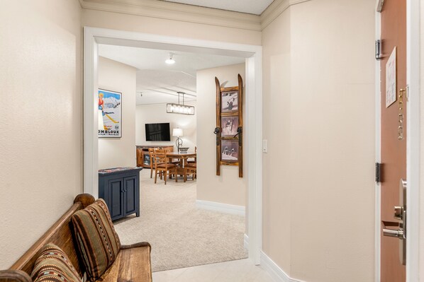 A hallway leading to a dining area with a wooden bench, a cabinet, and a wall-mounted picture frame.