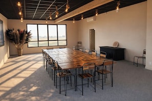 A conference room with a large wooden table, chairs, a black podium, and a large window with a view.
