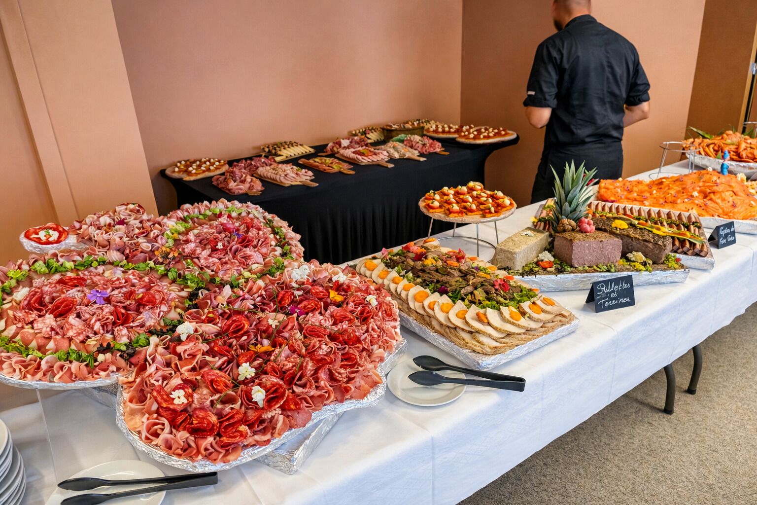 A buffet table with various food items and a person in the background.