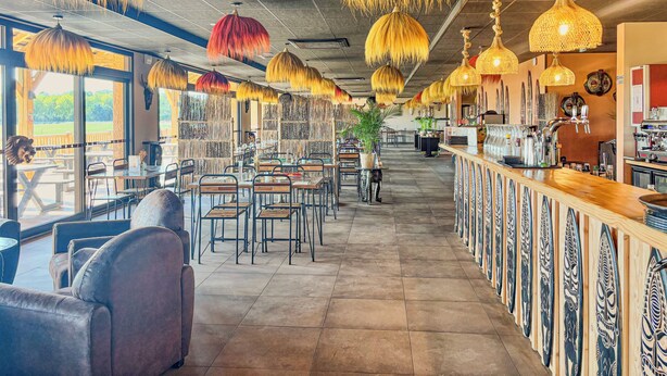 A restaurant interior with high ceilings, hanging lamps, and a bar area. - Le royaume des Lions  (Lumigny-Nesles-Ormeaux)