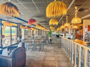 A restaurant interior with high ceilings, hanging lamps, and a bar area. - Le royaume des Lions  (Lumigny-Nesles-Ormeaux)