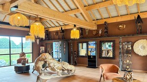 A spacious interior with a large wooden ceiling, a lion sculpture centerpiece, and a modern reception desk. - Le royaume des Lions  (Lumigny-Nesles-Ormeaux)