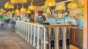 A bar area with a long counter, hanging rattan lamps, and wooden carvings. - Le royaume des Lions  (Lumigny-Nesles-Ormeaux)