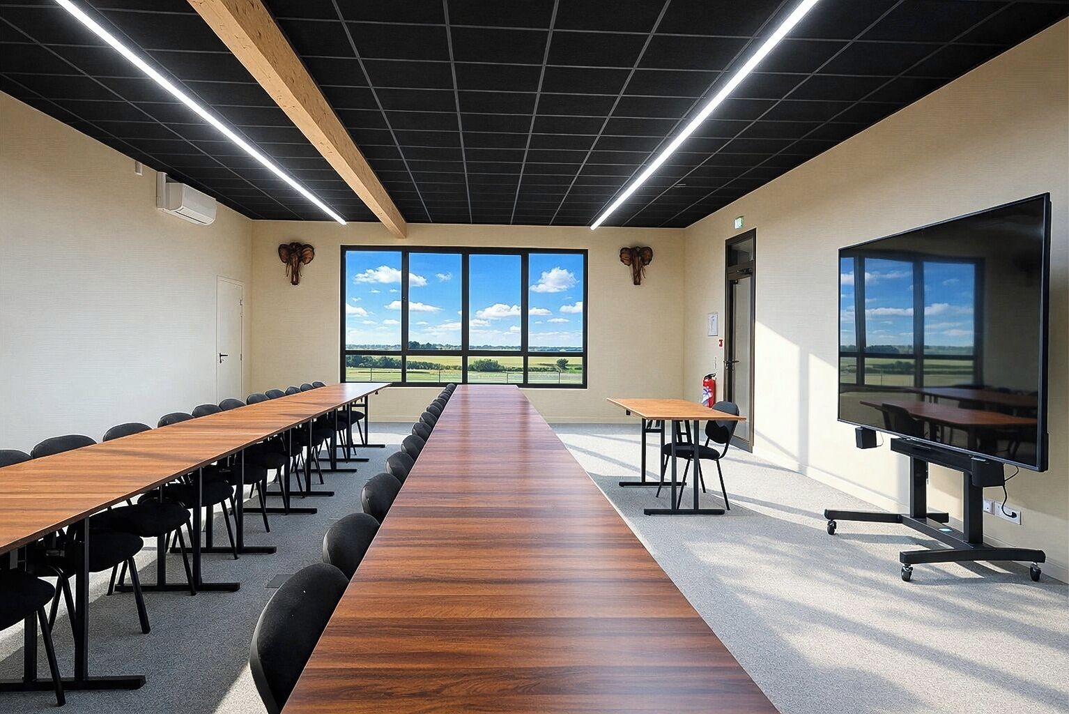 A conference room with a long table, chairs, a projector, and large windows with a view.