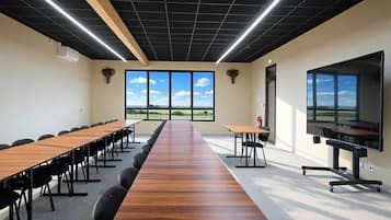 A conference room with a long table, chairs, a projector, and large windows with a view.