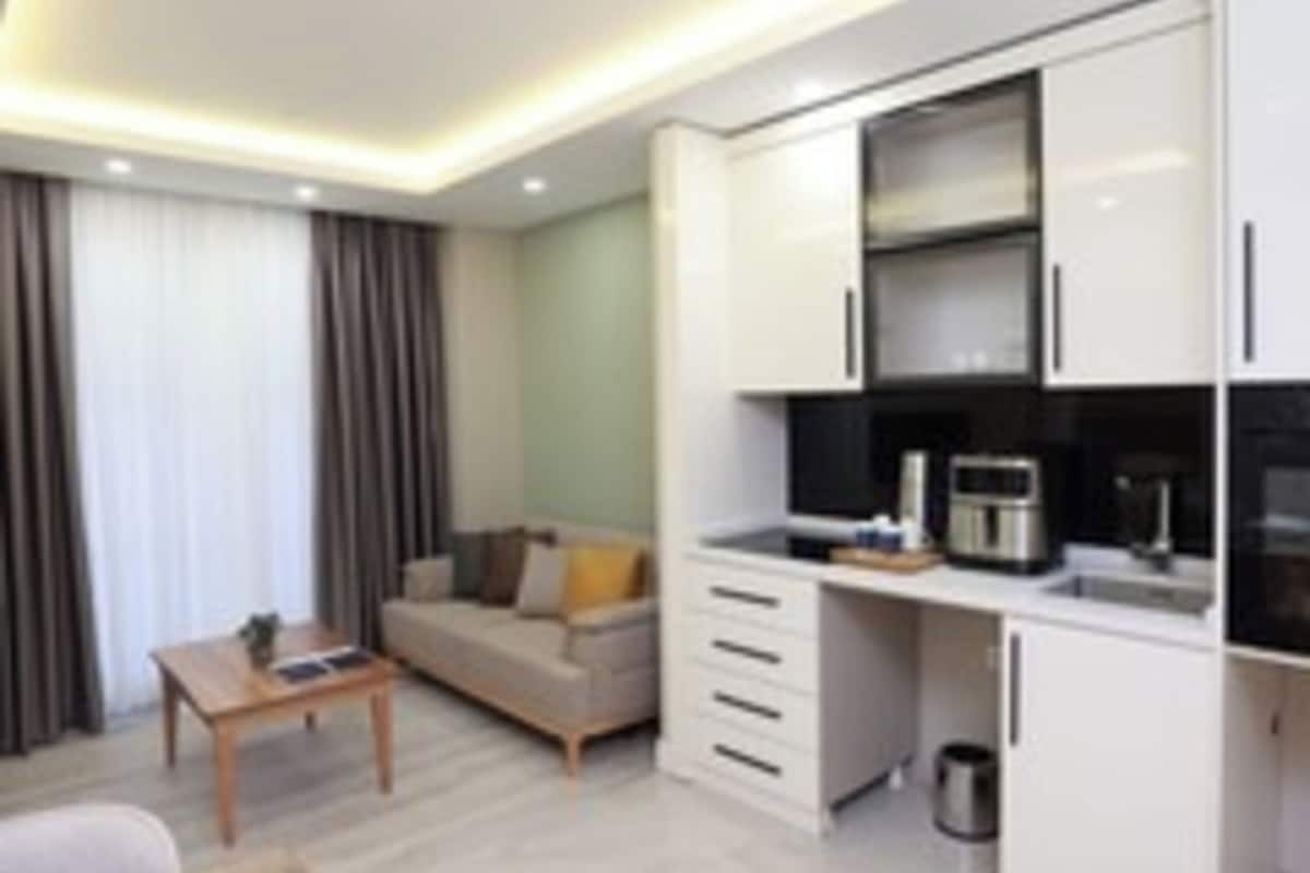 A modern hotel room with a living area, kitchenette, and a dining table.
