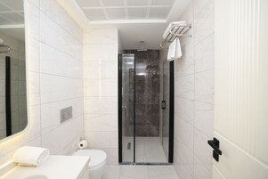 Un baño moderno con ducha de vidrio, inodoro y lavamanos con barra para toallas.