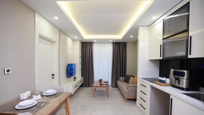 A modern living room with a dining area, a sofa, a TV, and a kitchen with a microwave.