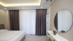 A modern bedroom with a bed, bedside table, and a large mirror.