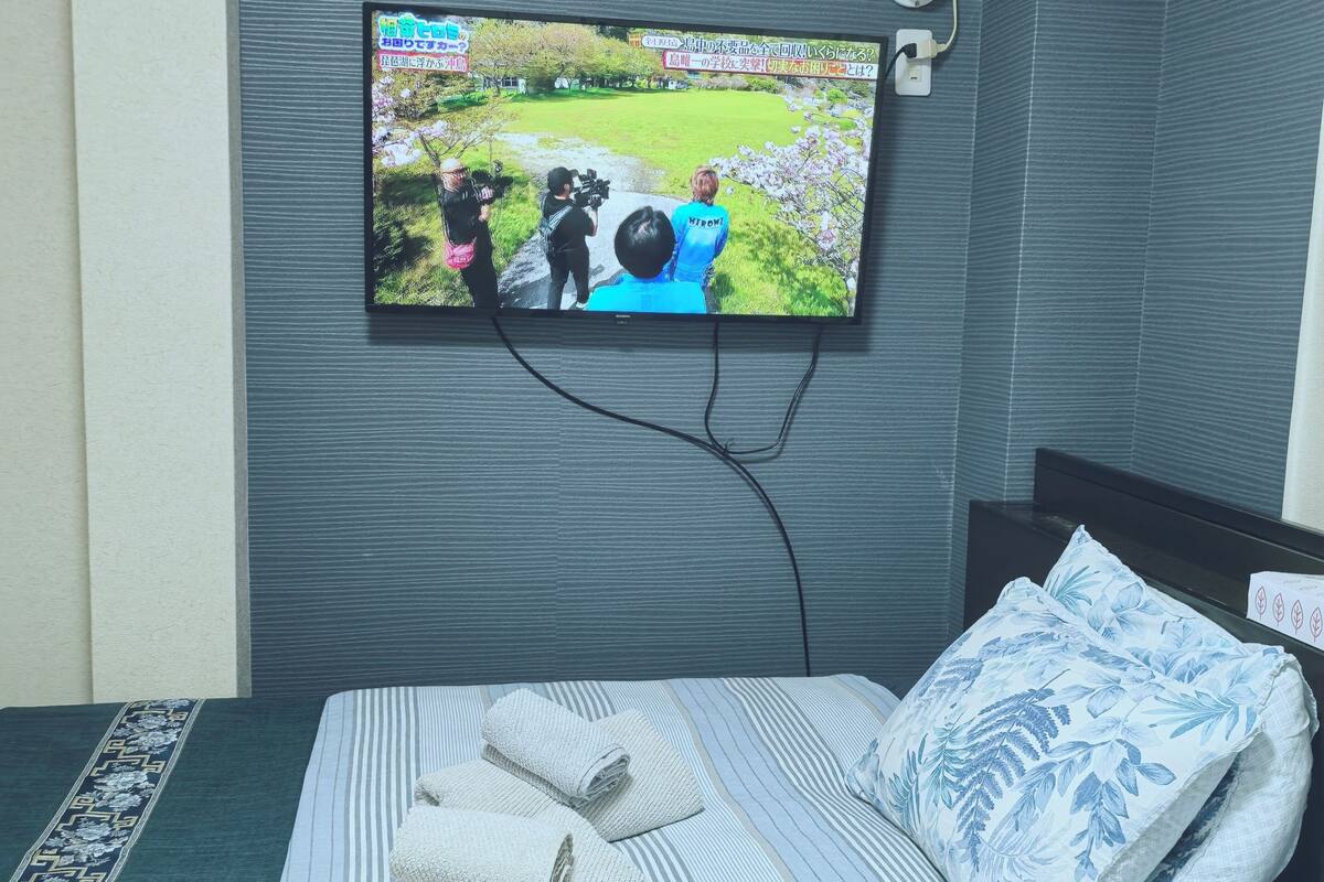 Une chambre d’hôtel avec un lit, un téléviseur fixé au mur et une fenêtre.