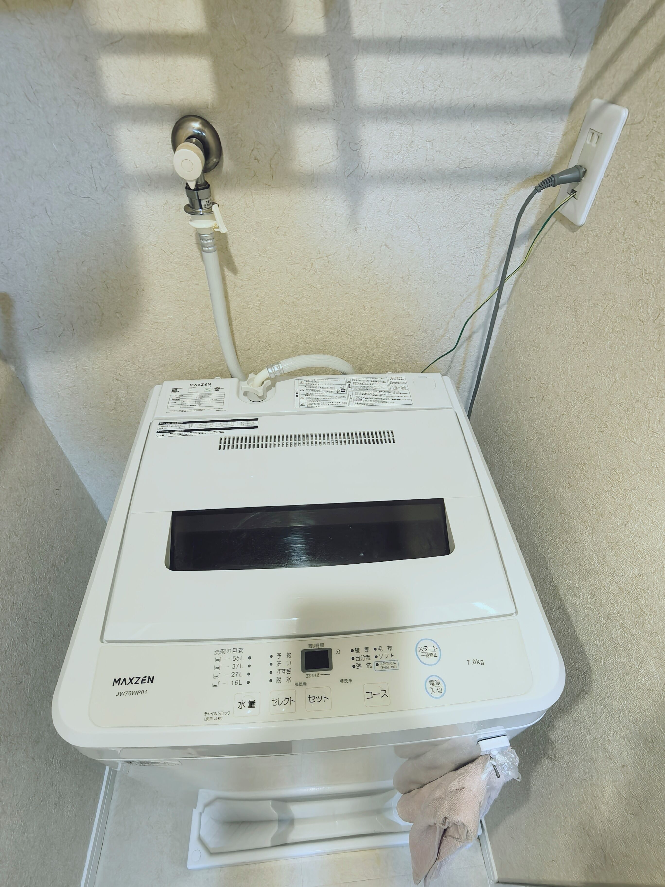 Een witte boiler met een digitaal scherm, aangesloten op een stopcontact.