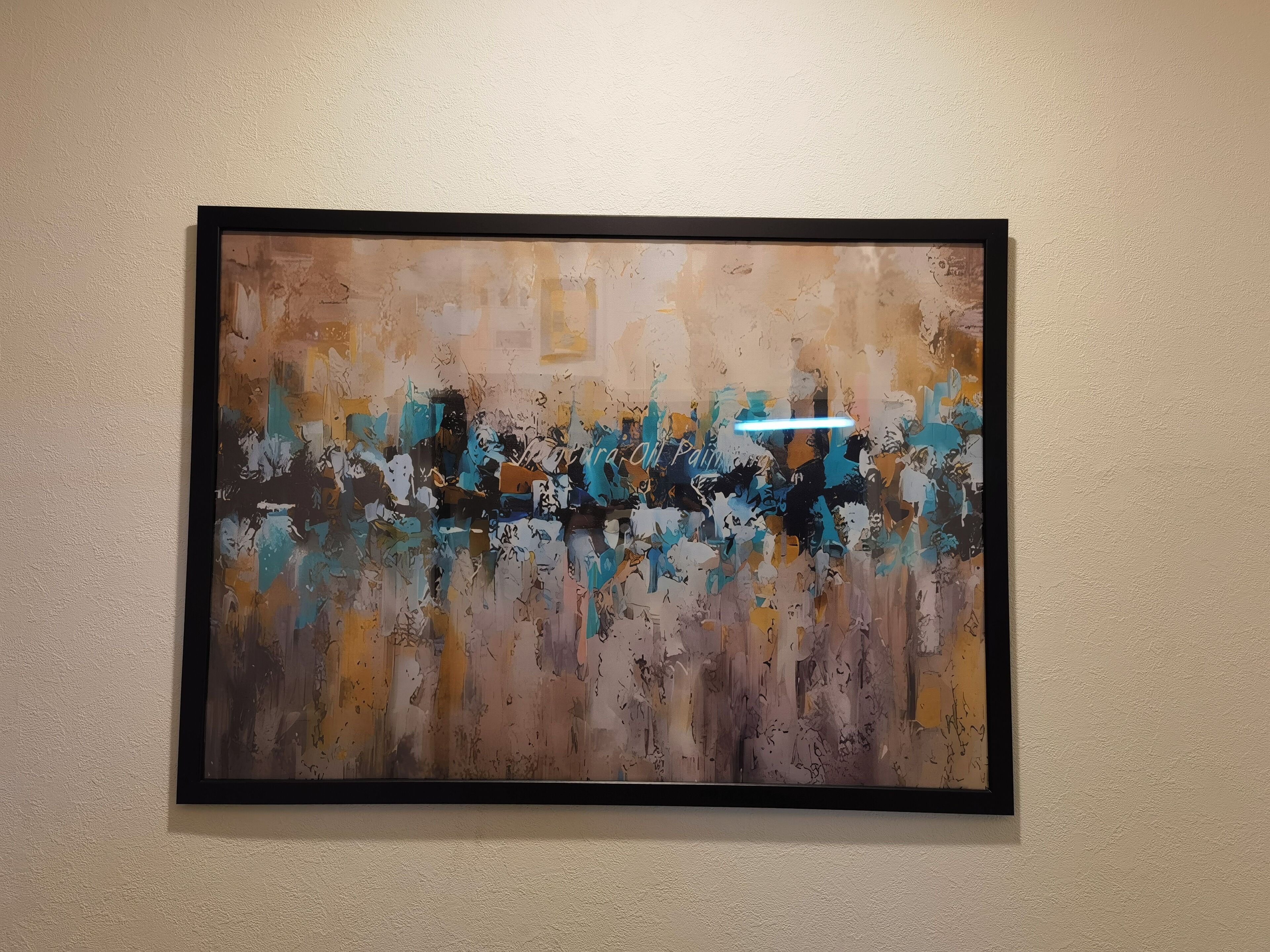 A framed abstract painting on a textured wall.