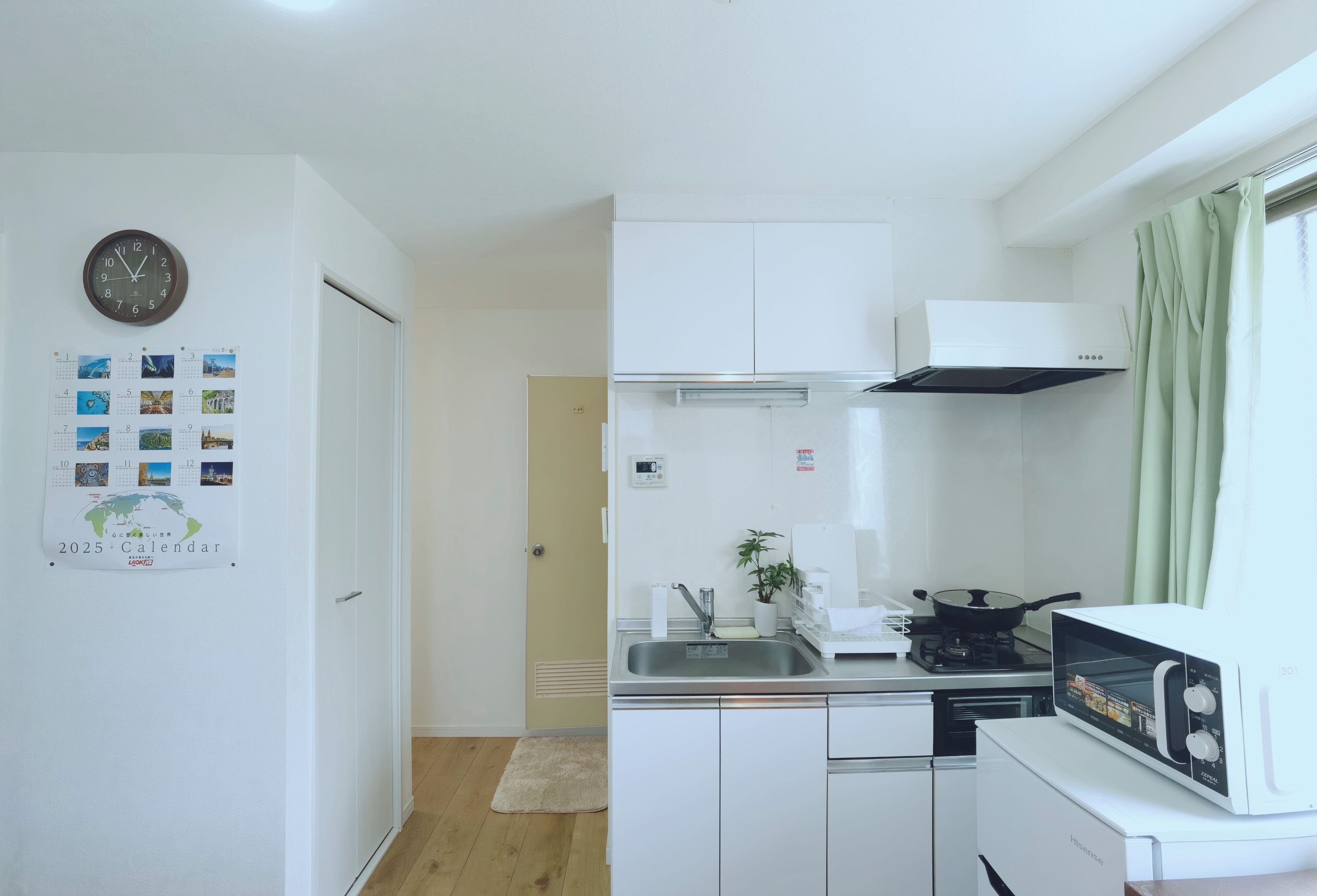 Une cuisine de taille réduite, avec des meubles blancs, un four à micro-ondes, un évier et une cuisinière.