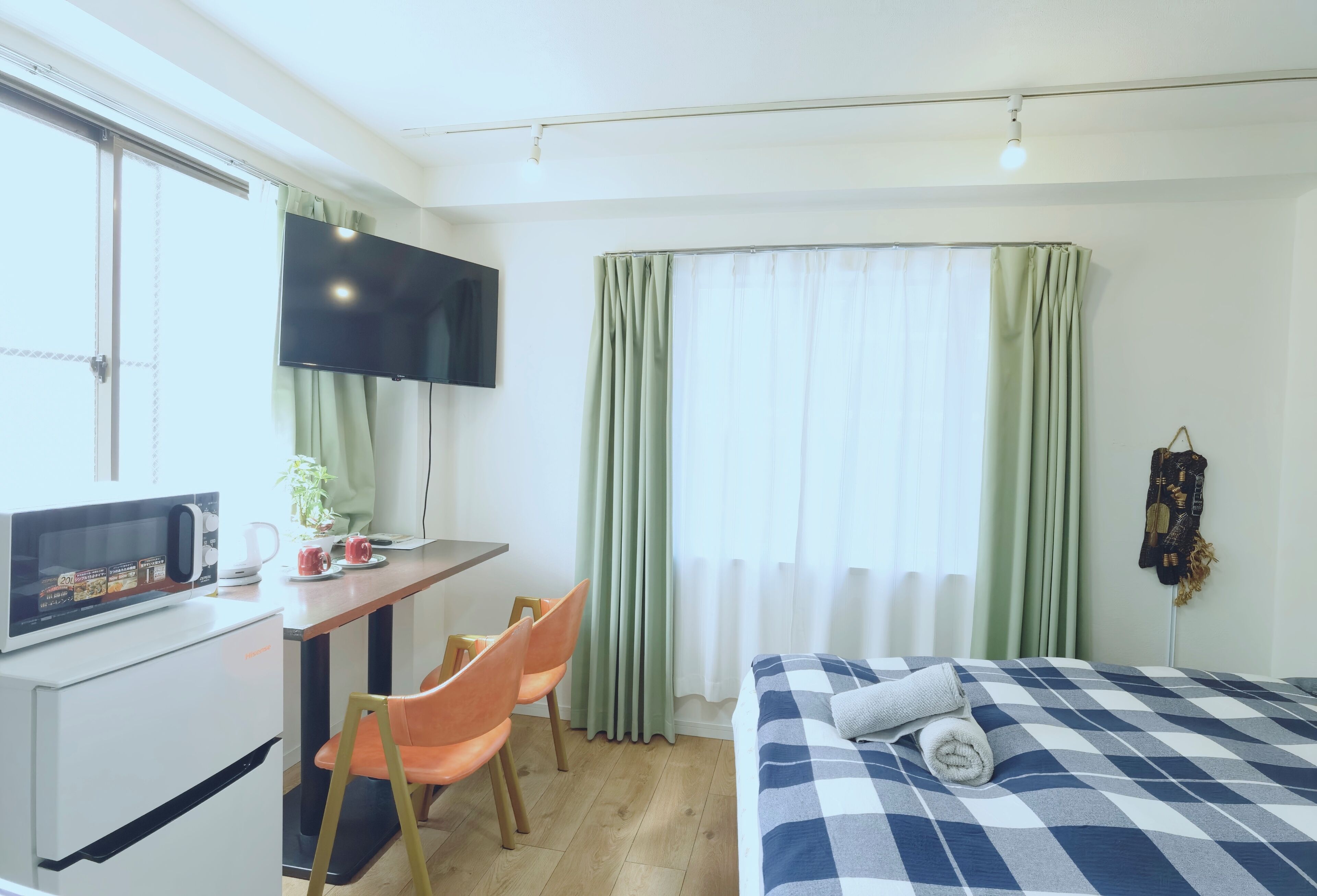 Et hotelværelse med seng, skrivebord med tv, mikroovn og stol.