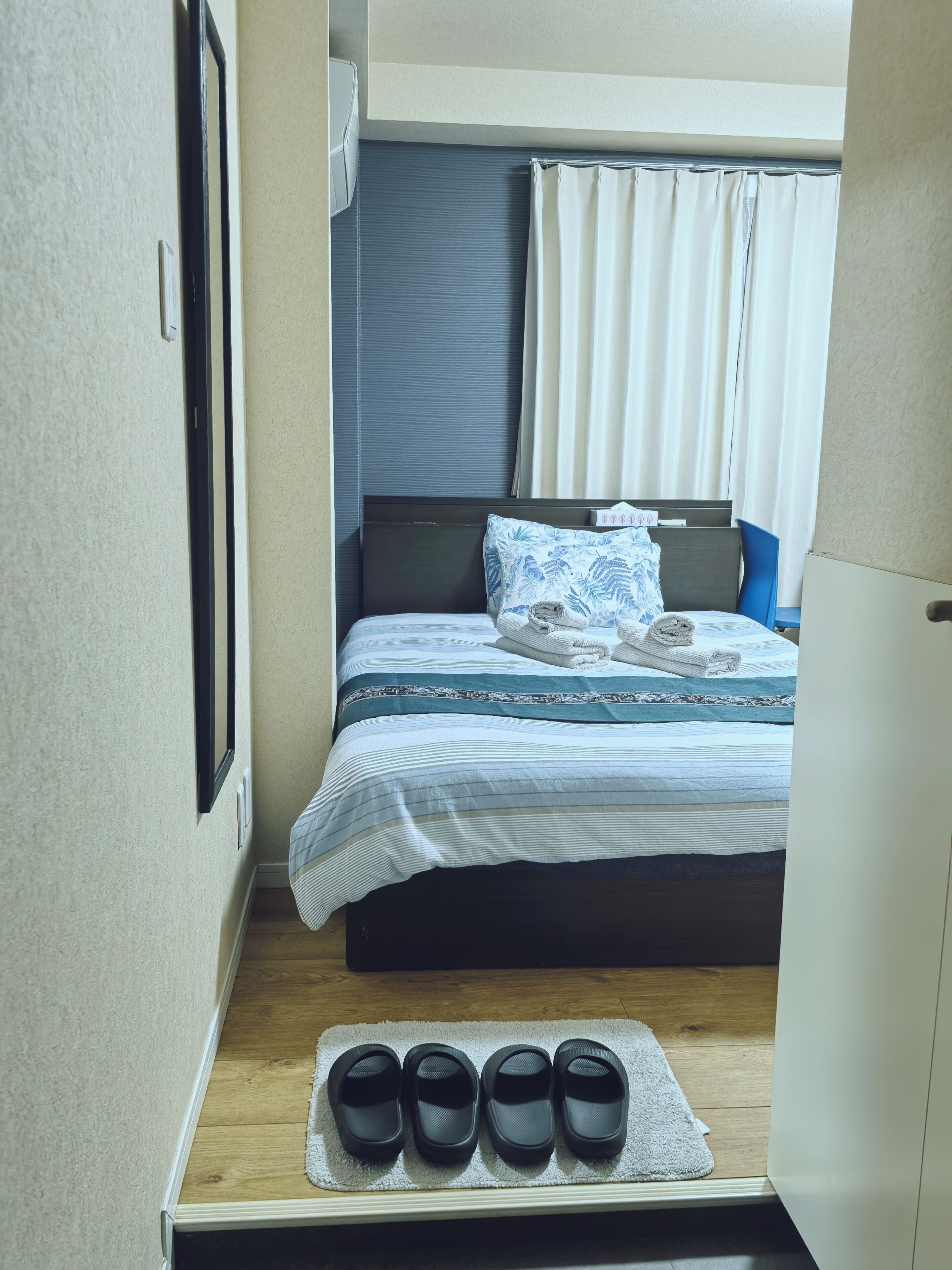 Quarto compacto com cama, um pequeno espaço para sentar e um sapateiro.