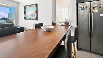 Una cocina moderna con una mesa de madera, sillas, un refrigerador y una ventana con vistas a la ciudad.