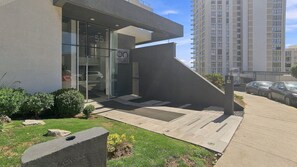 A modern building with a glass entrance, a concrete ramp, and a parking area.