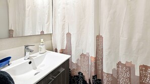 Un baño con lavamanos blanco, un espejo y una botella de jabón.