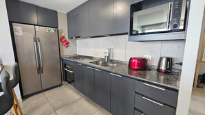 Una cocina moderna con electrodomésticos de acero inoxidable, un microondas, un tostador rojo y un fregadero.