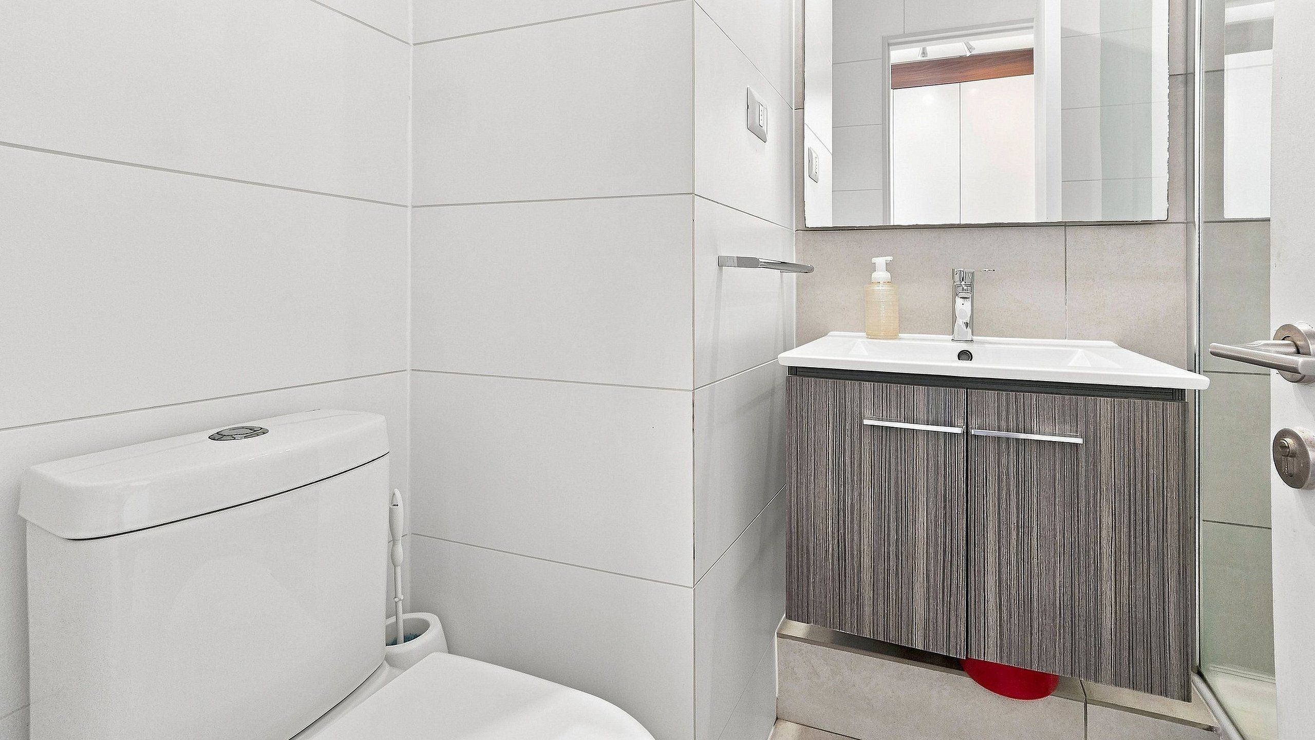 Une salle de bain comprenant des toilettes, un lavabo avec un miroir et un meuble de rangement.