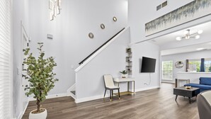 Un salon moderne avec un escalier, un téléviseur à écran plat et un canapé bleu.
