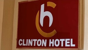 A hotel sign with a red background and a white and gold logo. - Clinton Hotel (Kikuyu)
