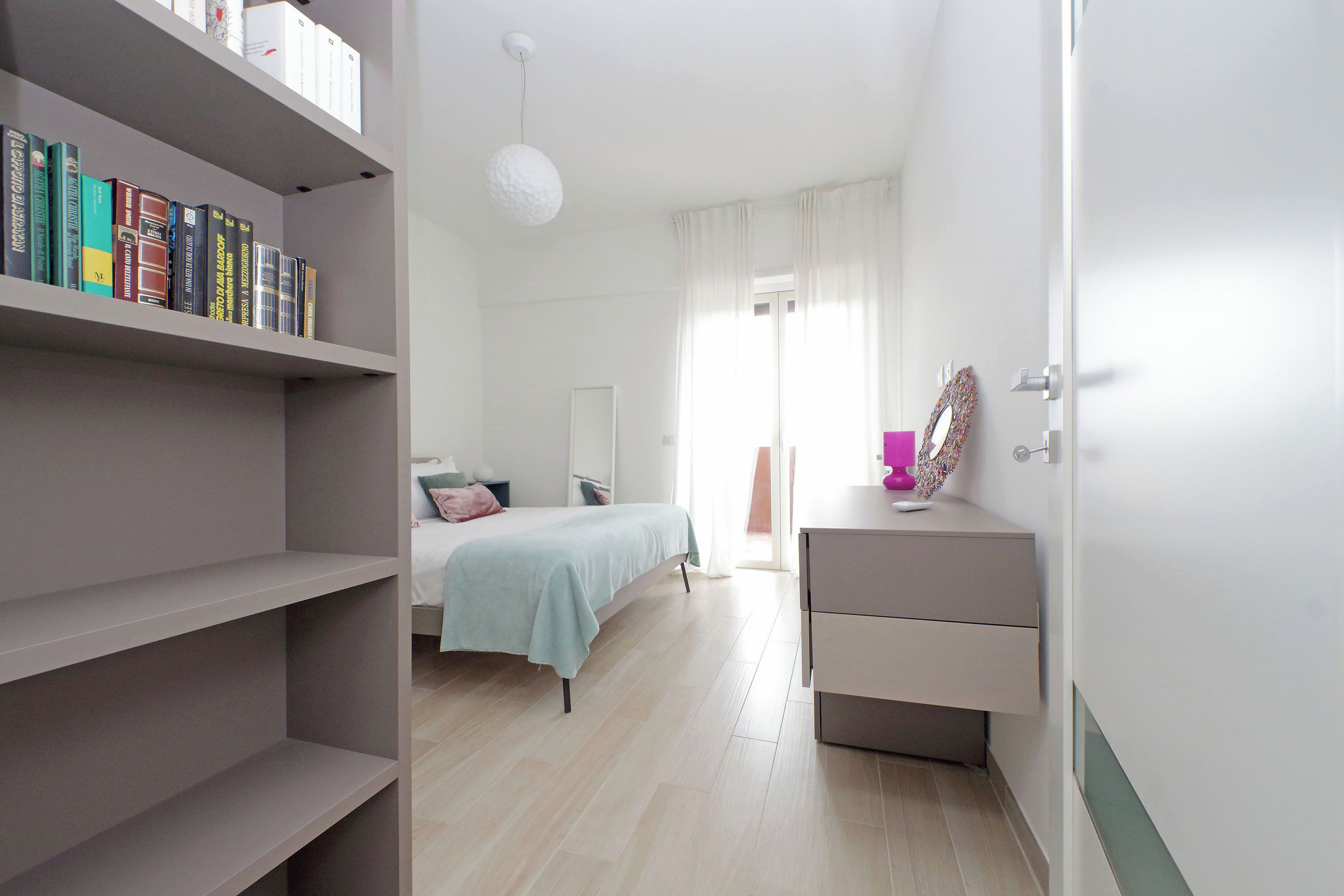 A bedroom with a bed, bedside table, and a bookshelf.