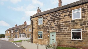 A row of stone houses with uniform architecture, featuring multiple windows and doors, and a clear sky. - Host & Stay | The Braes (Marske-by-the-Sea)