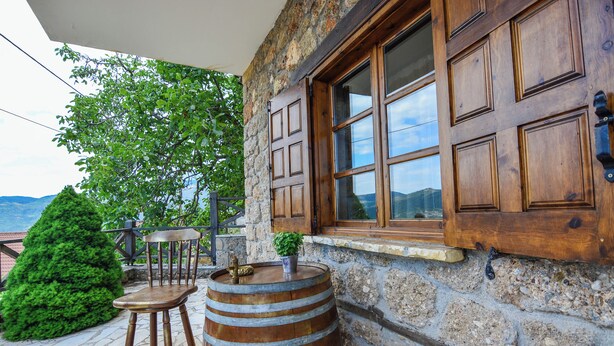 A stone building with wooden shutters, a wooden barrel, and a small stool.