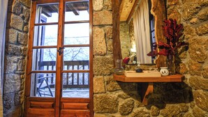 A stone wall interior with a wooden door and a shelf with decorative items.