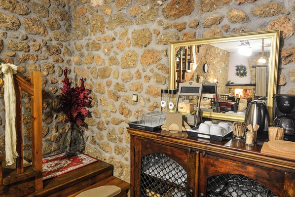 A stone-walled room with a wooden bench, a mirror, and a fireplace. - Petrino Lodge (Xylokastro-Evrostina)