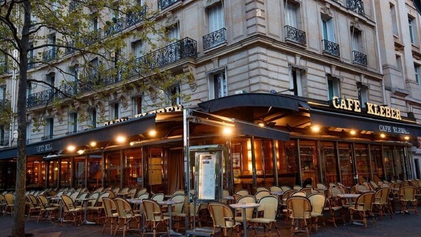 Un café con terraza, una zona cubierta y una fachada con balcones.