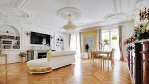 Amplia sala de estar con un sofá blanco, chimenea y comedor con mesa y sillas.