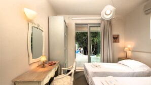Ein Hotelzimmer mit zwei Betten, einem Schreibtisch mit Stuhl, einem Spiegel und Blick ins Freie.